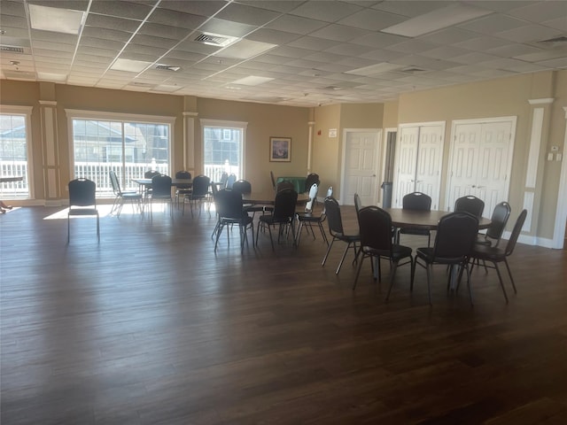 dining area with a paneled ceiling, visible vents, and dark wood finished floors