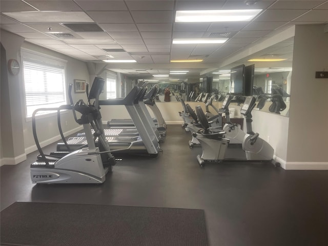 gym with a paneled ceiling, visible vents, and baseboards