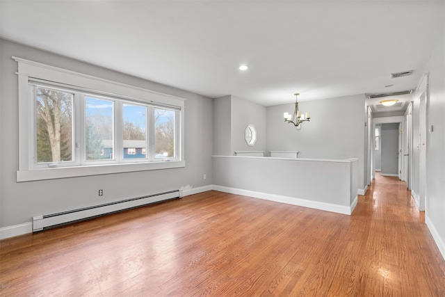 spare room featuring a chandelier, light hardwood / wood-style flooring, and a baseboard radiator