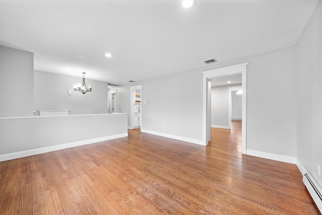 unfurnished living room featuring a chandelier, a baseboard radiator, and hardwood / wood-style flooring