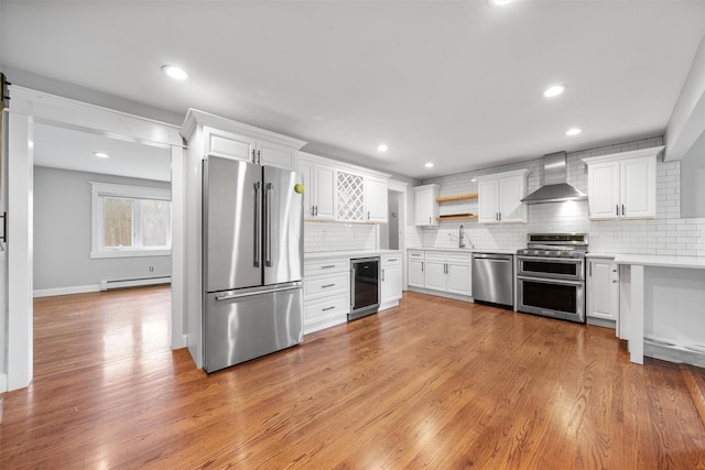 kitchen with stainless steel appliances, beverage cooler, wall chimney range hood, light hardwood / wood-style flooring, and white cabinets