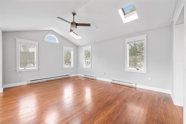 empty room featuring hardwood / wood-style flooring, ceiling fan, vaulted ceiling with skylight, and a baseboard radiator