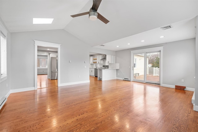 unfurnished living room featuring ceiling fan, light wood-type flooring, baseboard heating, and lofted ceiling with skylight