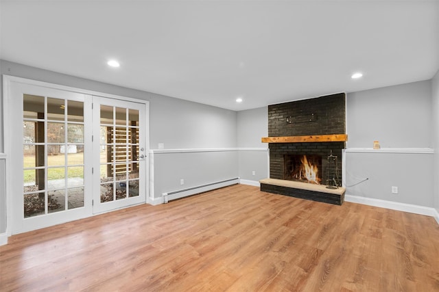 unfurnished living room featuring a baseboard radiator, light wood-type flooring, and a brick fireplace