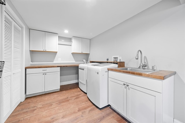 laundry room with cabinets, sink, washer and dryer, and light wood-type flooring