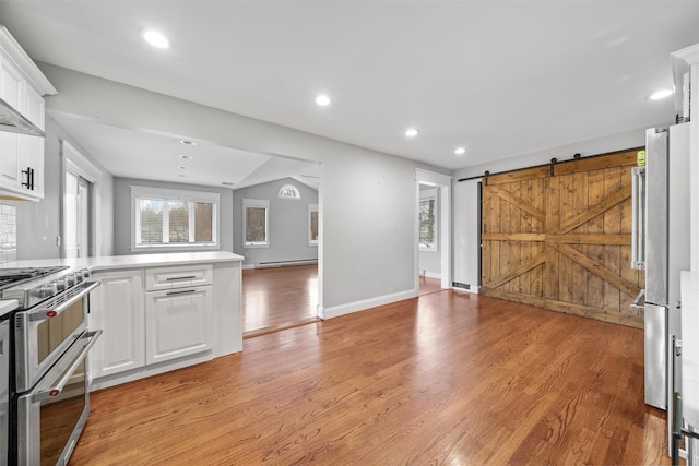 kitchen with stainless steel appliances, a barn door, a baseboard radiator, light hardwood / wood-style flooring, and white cabinets