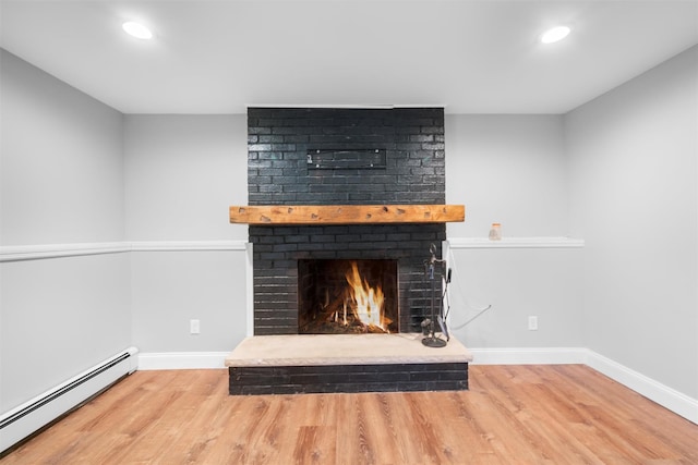 room details with baseboard heating, a fireplace, and hardwood / wood-style floors