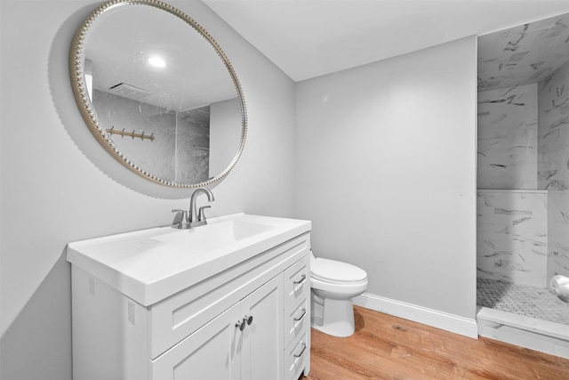 bathroom featuring a tile shower, toilet, vanity, and hardwood / wood-style flooring