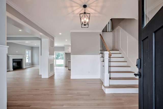 entrance foyer featuring light wood-type flooring, crown molding, and an inviting chandelier