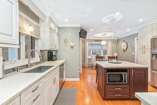 kitchen with white cabinetry, sink, ornamental molding, and stainless steel appliances