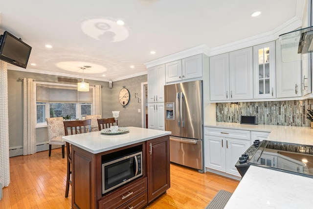 kitchen with hanging light fixtures, crown molding, white cabinets, and appliances with stainless steel finishes