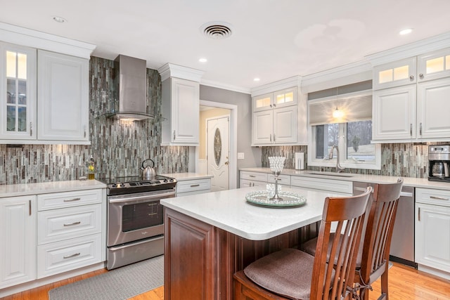 kitchen featuring wall chimney range hood and white cabinets