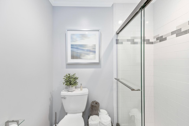 bathroom with ornamental molding, toilet, and a shower with shower door