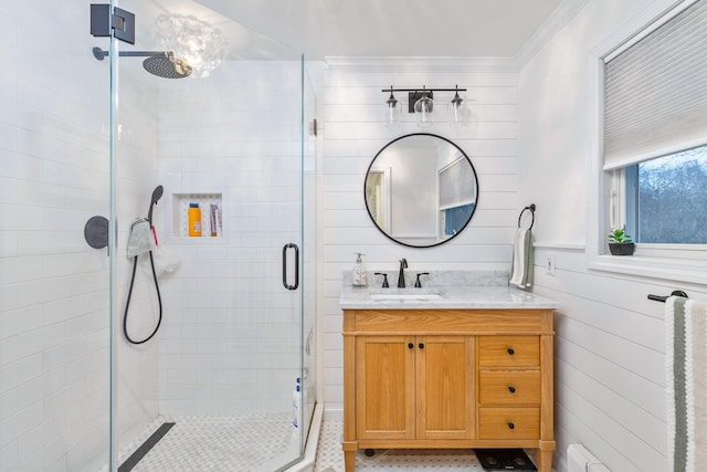 bathroom with vanity, crown molding, a shower with shower door, and wooden walls