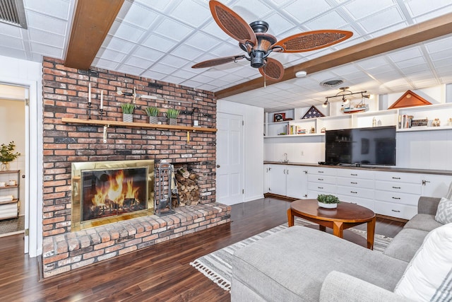 living room featuring dark hardwood / wood-style flooring, a brick fireplace, and ceiling fan