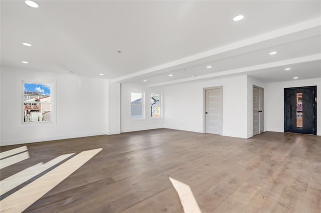 empty room with hardwood / wood-style floors and beam ceiling