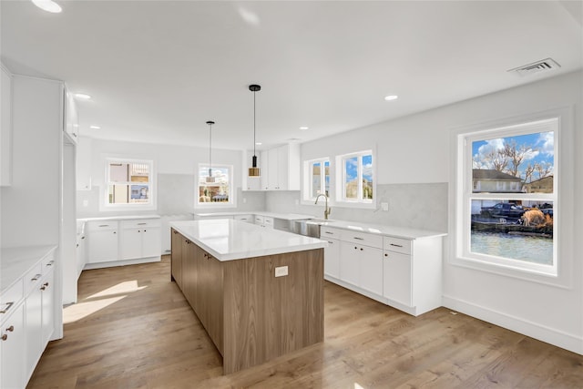 kitchen featuring white cabinetry, sink, a kitchen island, and light wood-type flooring