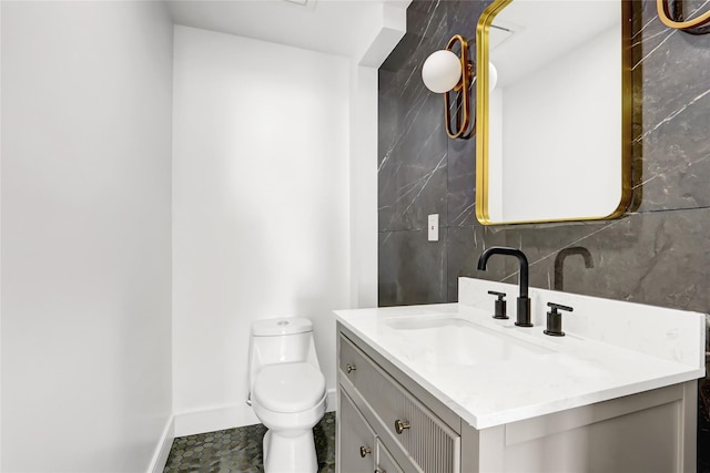 bathroom with vanity, tile walls, and toilet