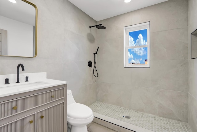 bathroom with tile patterned floors, vanity, a tile shower, and toilet