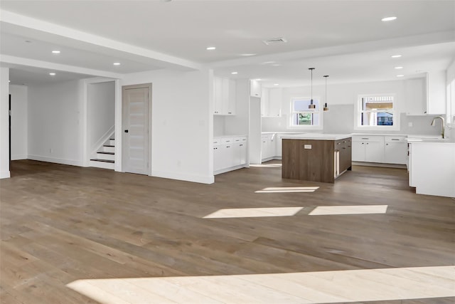 kitchen featuring white cabinetry, a kitchen island, hanging light fixtures, and hardwood / wood-style flooring