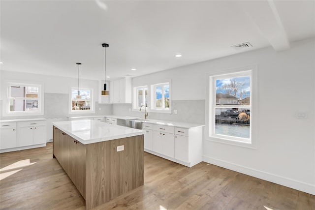 kitchen with a wealth of natural light, white cabinetry, and a center island