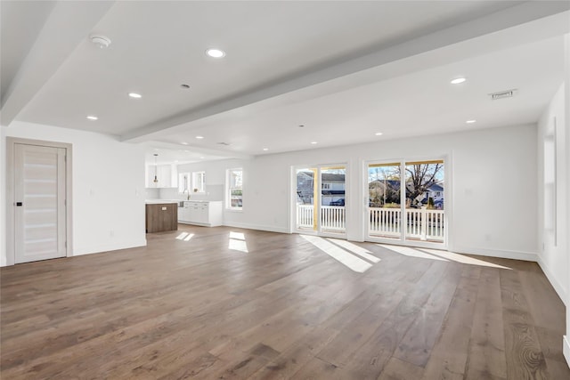 unfurnished living room featuring beamed ceiling, wood-type flooring, and sink