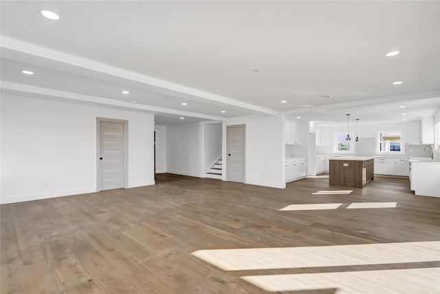 unfurnished living room with beamed ceiling, dark hardwood / wood-style flooring, and sink