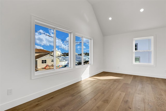 spare room with light hardwood / wood-style floors and lofted ceiling