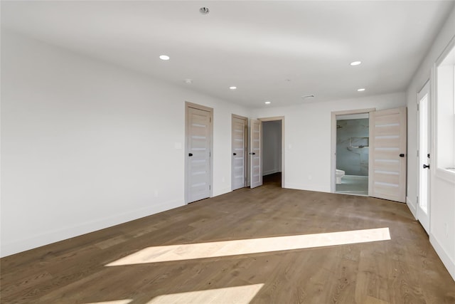 unfurnished bedroom with ensuite bath and wood-type flooring