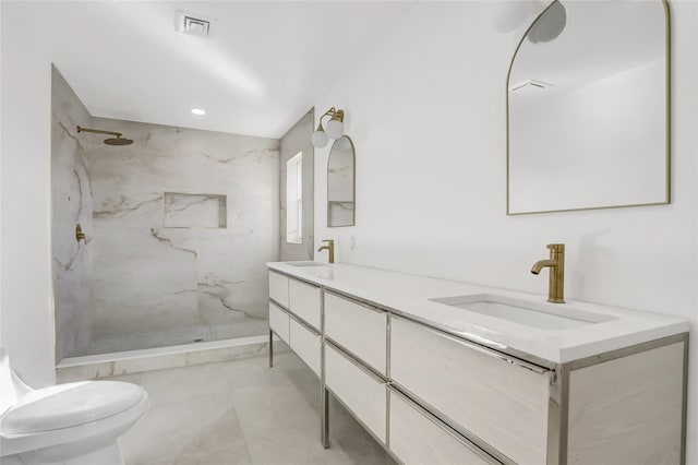 bathroom featuring a tile shower, vanity, and toilet