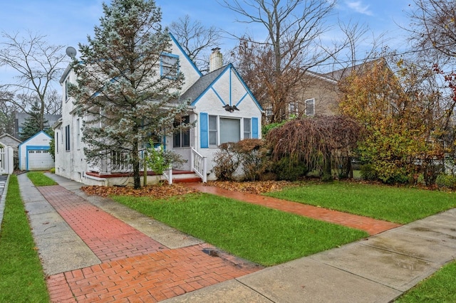 view of front of home with a front yard, an outdoor structure, and a garage