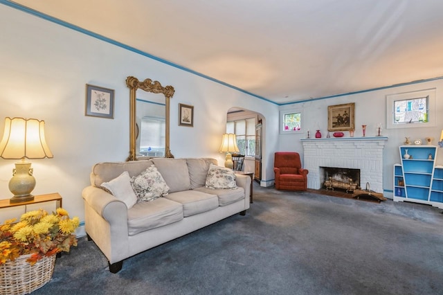 living room featuring a fireplace, dark carpet, and crown molding