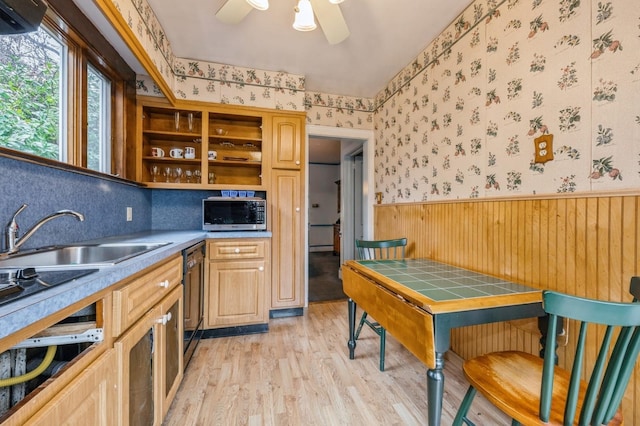 kitchen with sink, ceiling fan, black dishwasher, tile counters, and light hardwood / wood-style floors