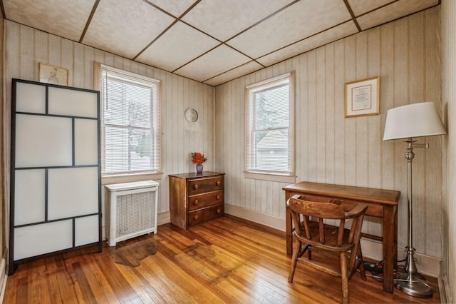 interior space with radiator, a paneled ceiling, and hardwood / wood-style flooring