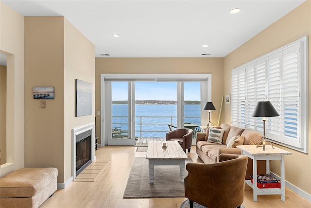 living room featuring a water view and light hardwood / wood-style flooring