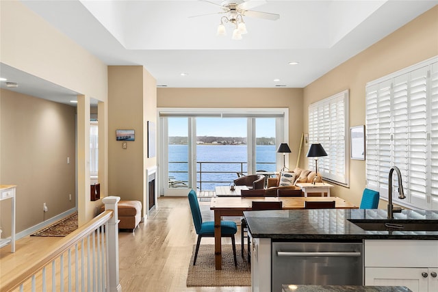 kitchen with ceiling fan, sink, light hardwood / wood-style flooring, a water view, and white cabinets