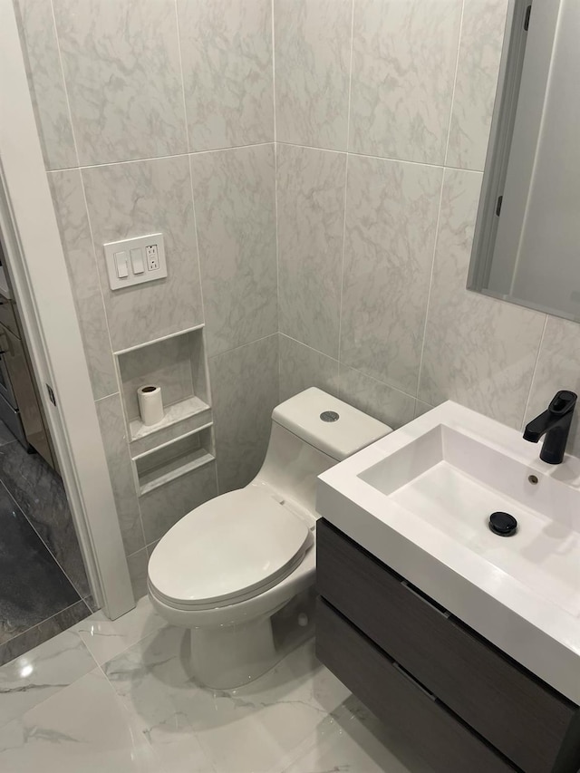 bathroom with vanity, toilet, and tile walls