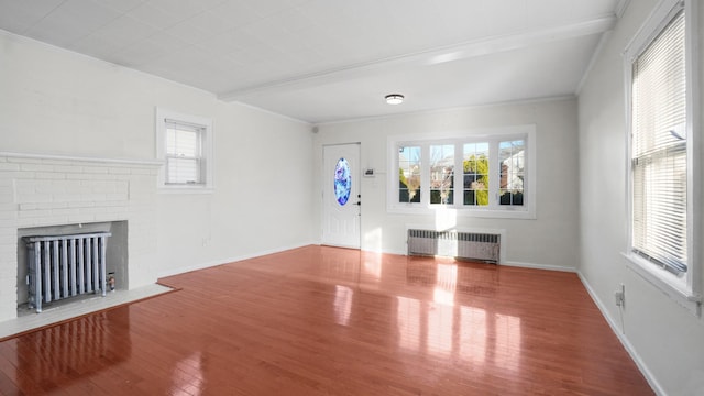 unfurnished living room with radiator, a healthy amount of sunlight, and wood-type flooring