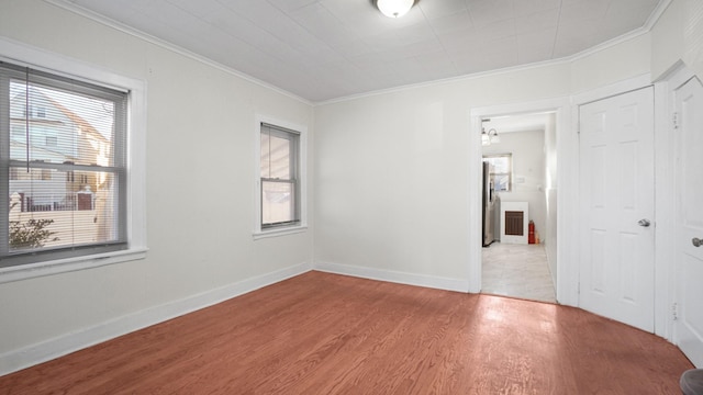 empty room with a chandelier, ornamental molding, and light hardwood / wood-style flooring