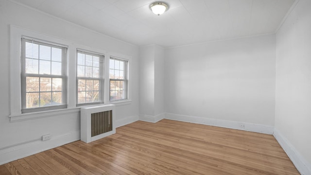 empty room with light hardwood / wood-style flooring, radiator, and ornamental molding