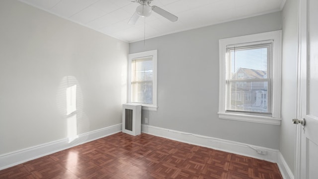 unfurnished room featuring dark parquet floors, ceiling fan, and a healthy amount of sunlight