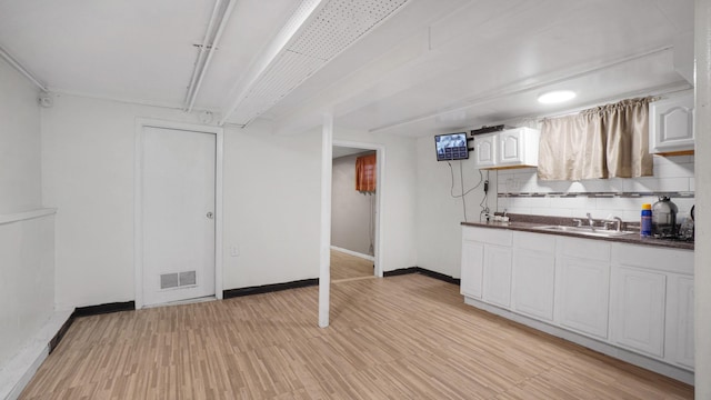 kitchen featuring white cabinets, tasteful backsplash, sink, and light hardwood / wood-style flooring