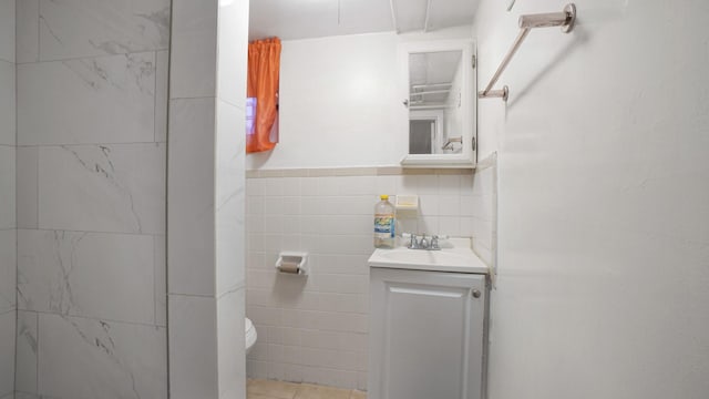 bathroom featuring vanity, toilet, and tile walls