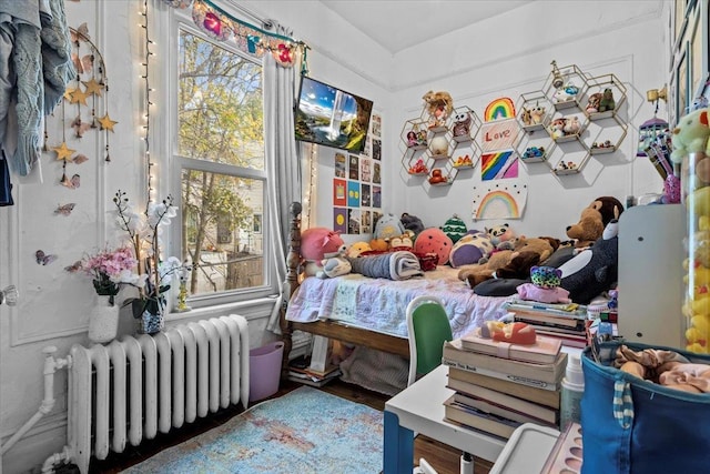 bedroom featuring hardwood / wood-style flooring, radiator heating unit, and multiple windows