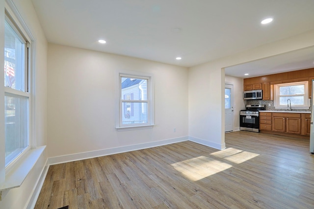 kitchen with sink, light wood-type flooring, stainless steel appliances, and backsplash