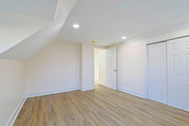 additional living space featuring light wood-type flooring and vaulted ceiling