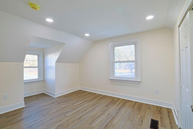 additional living space featuring lofted ceiling, light hardwood / wood-style flooring, and plenty of natural light