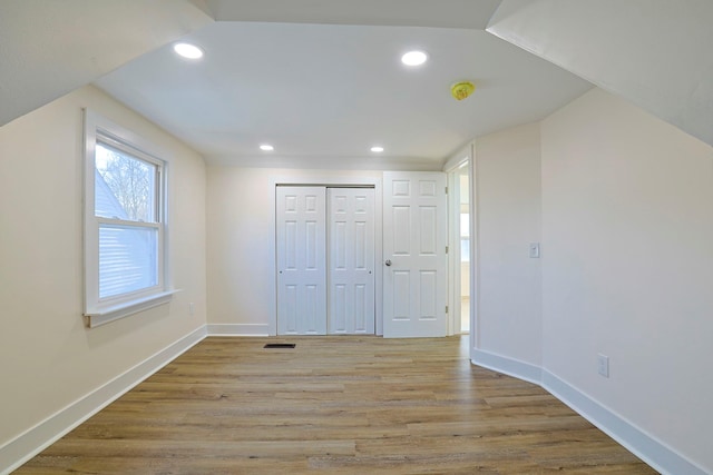 unfurnished bedroom featuring vaulted ceiling, light wood-type flooring, and a closet