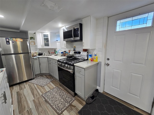 kitchen featuring white cabinets, sink, light wood-type flooring, and stainless steel appliances