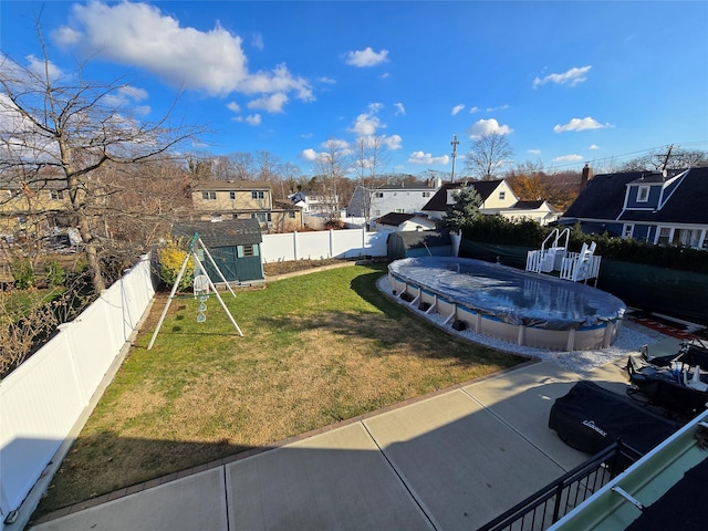 view of yard with a patio, a covered pool, and a storage unit